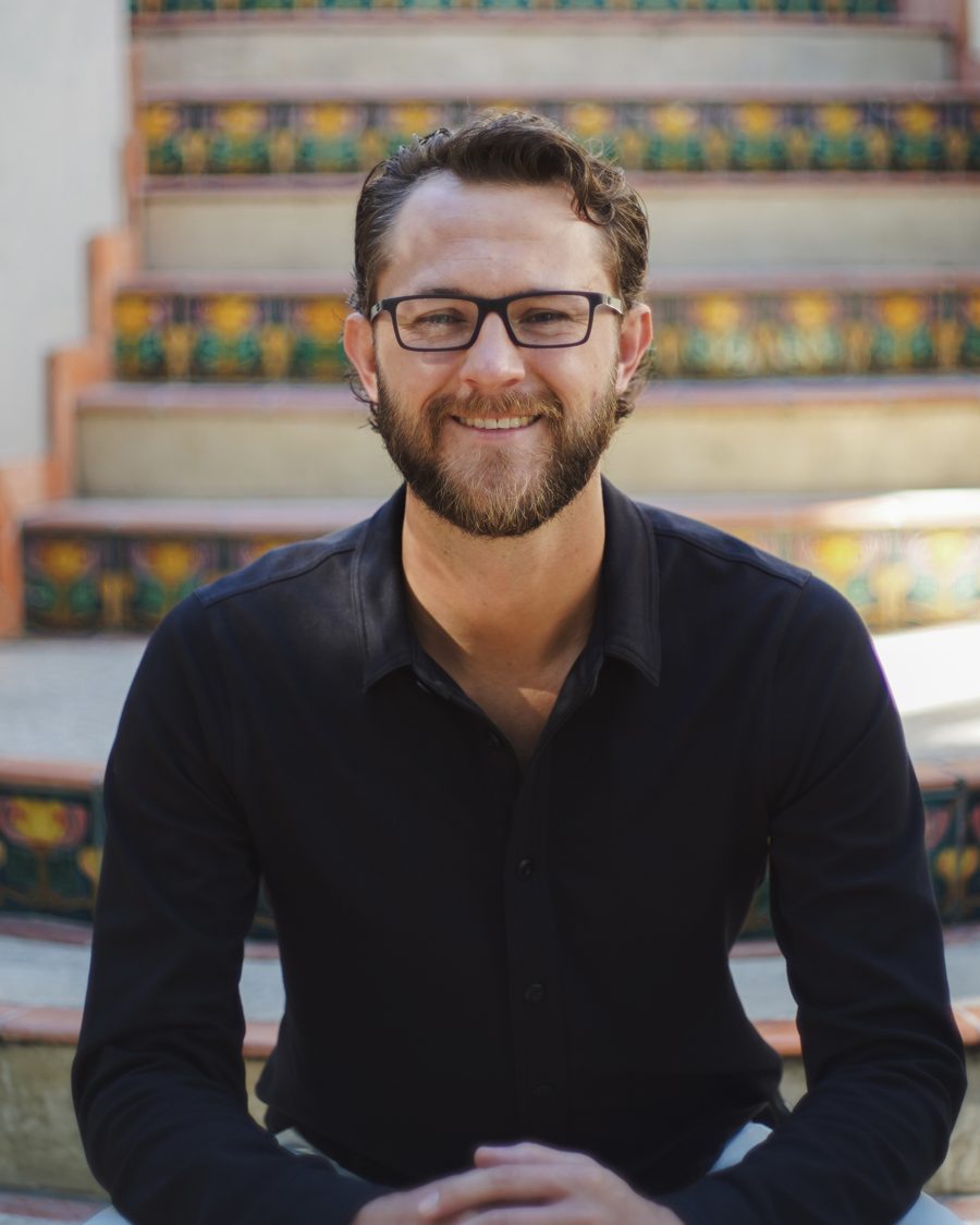 Ted Lindblom, smiling, sitting on a tiled staircase